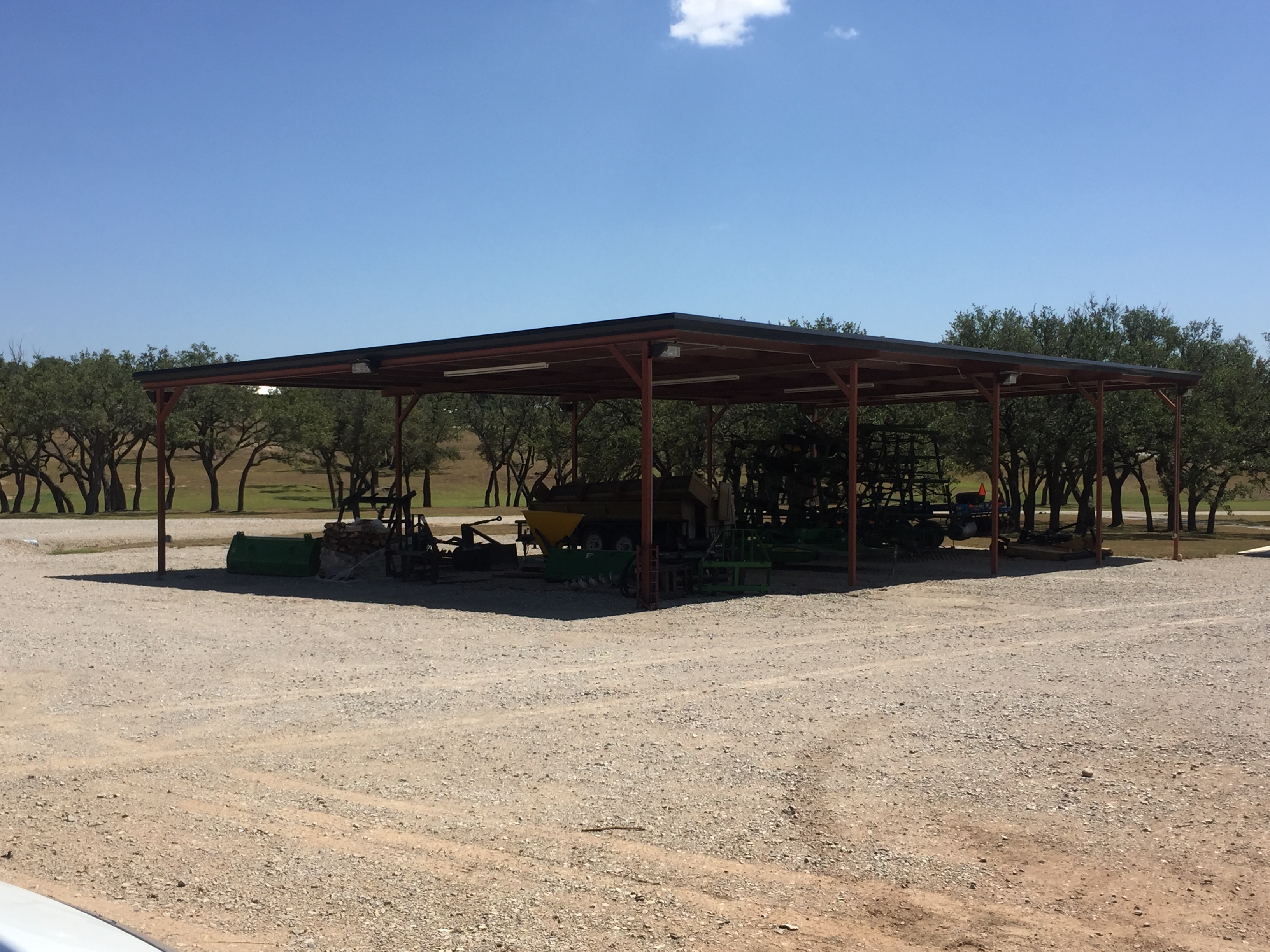 Open-sided metal equipment shed with red steel posts by Frank Valdez Fencing